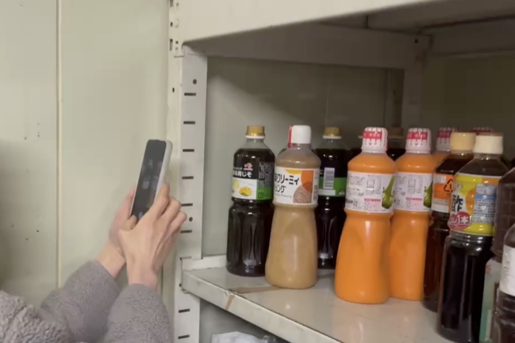調味料が並ぶ棚の前で、スマートフォンを向けて撮影している様子
