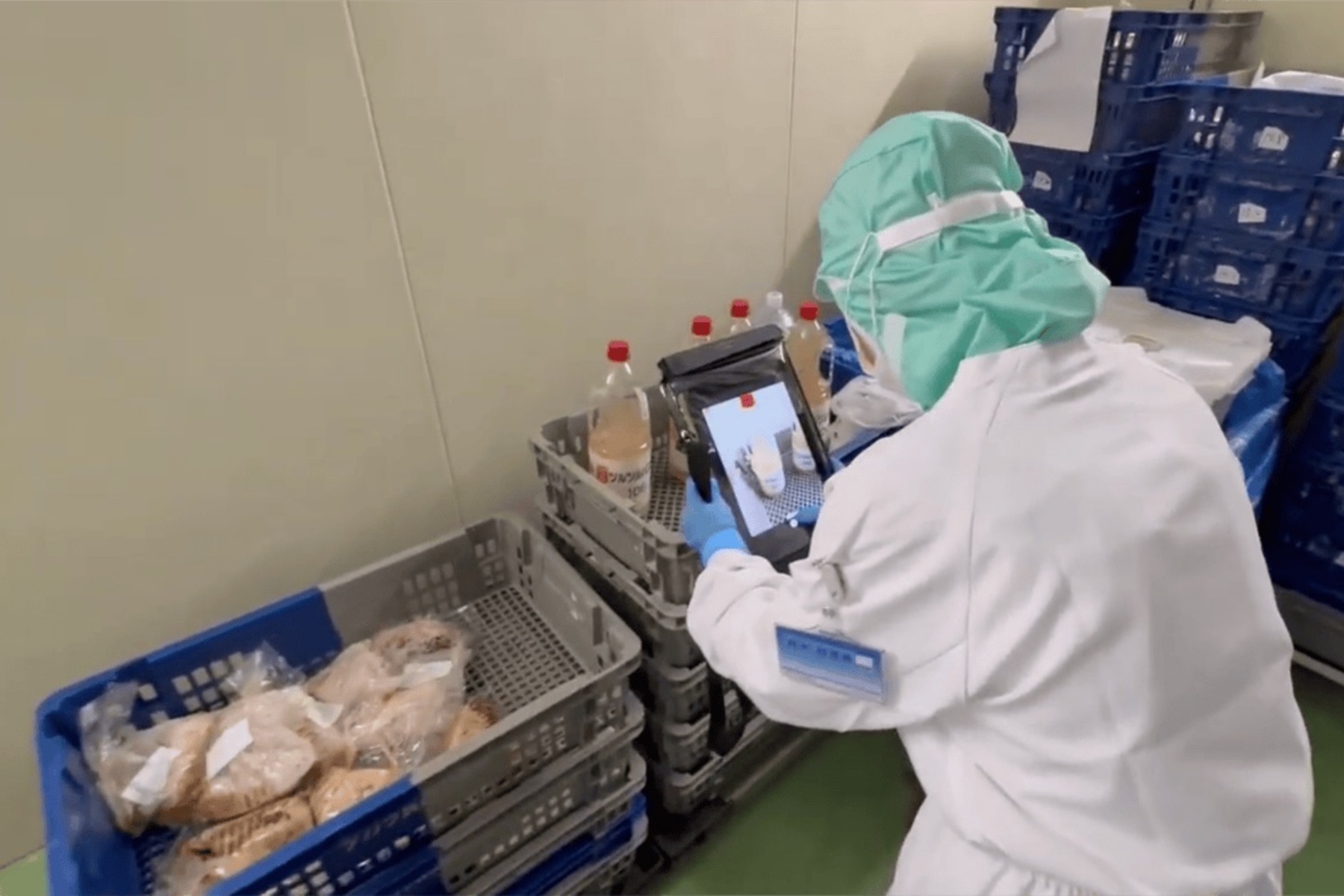 食品工場で白衣の作業者がタブレットを使って商品を撮影している様子